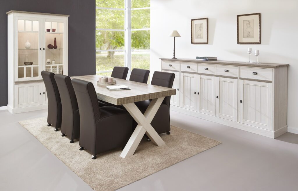Lichte eethoek met robuuste houten tafel, zes zwarte stoelen, witte dressoir en vitrinekast, meubels van Belga Meubel Brugge