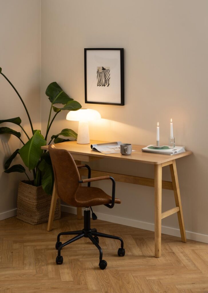 Moderne werkhoek met houten bureau, leren bureaustoel, tafellamp, planten en kaarsen, meubels van Belga Meubel Brugge